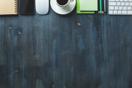 Top view of textured wooden desk top with smartphone, supplies, keyboard and other items. Copy spaceの写真素材