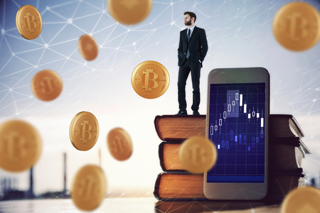 Businessman standing on book stack with forex chart on smartphone screen. Blurry city backgrond with falling golden bitcoins and polygonal network. Cryptography and market concept. Double exposure の写真素材