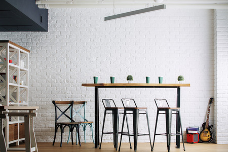 Contemporary interior with table, chairs and other furniture, white brick wall and guitar. Hobby,...