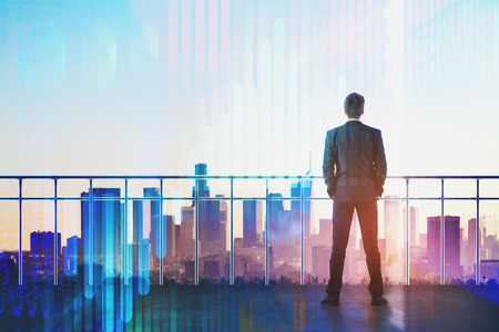 Back view of young businessman on rooftop with business chart hologram. Futuristic innovation and finance concept. Double exposure の写真素材