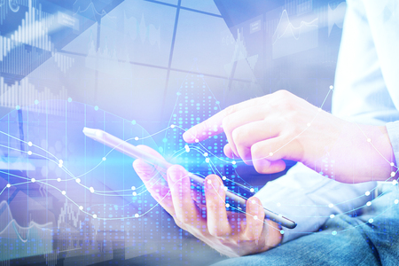 Close up of hand using tablet with abstract digital business hologram. Technology, innovation and network concept. Double exposureの写真素材