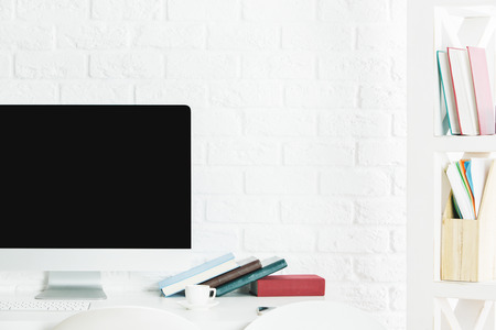 Modern desktop with blank white computer monitor, stationery items and other objects. Design and...