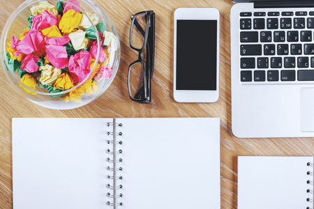 Top view of wooden office table with blank copybook, smartphone and other objects. Mock upの写真素材