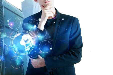 Attractive european businessman with creative business hologram standing on abstract city background. Finance and global concept. Double exposure の写真素材