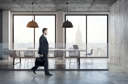 Side view of young businessman walking in contemporary meeting room interior with New York city view, equipment and daylight. 3D Rendering の写真素材