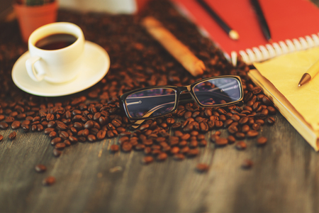 Close up of wooden table with coffee cup, beans, supplies and other items. Art, hobby, leisure, morning conceptの写真素材
