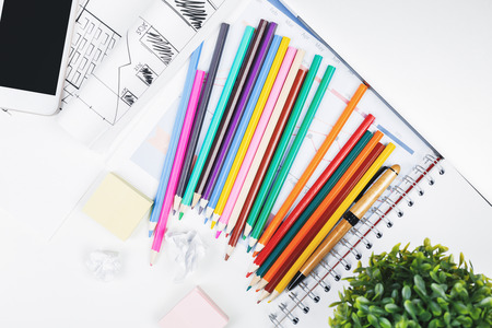 Top view of modern white office desk top with blank smartphone, supplies, architectural sketch and...