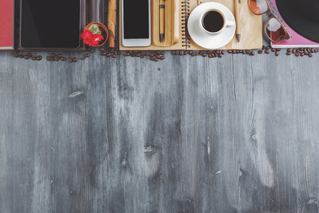 Top view of creative wooden desktop with coffee cup, beans, supplies and other items. Art, hobby, leisure, morning conceptの写真素材