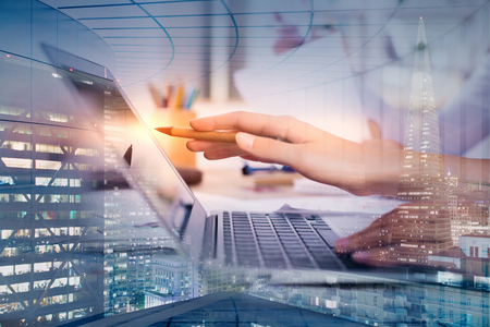 Side view of female hands using laptop on abstract city background. Technology and device concept. Double exposure の写真素材