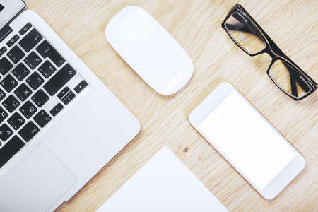 Mix of office supplies, laptop, smartphone and other items on modern wooden table top. Above view. Mock up の写真素材