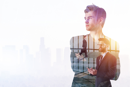 Success and technology concept. Thoughtful young businessman standing on abstract creative city office background with sunlight and copy space. Double exposure の写真素材