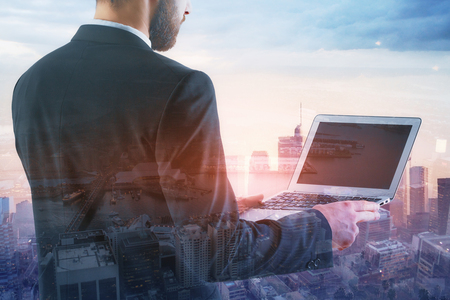 Businessman using empty laptop on abstract city background. Technology concept. Mock up, Double exposure の写真素材