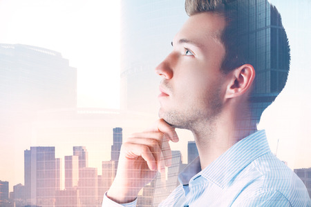 Portrait of attractive pondering young businessman on abstract city background with copy space. Employment and success concept. Double exposure の写真素材
