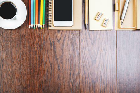 Top view and close up of shiny wooden office desktop with smartphone, supplies and other items. Mock upの写真素材
