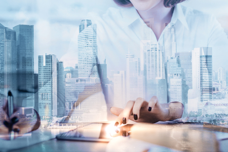 Businesswoman doing paperwork at abstract blurry workplace with city view. Double exposure の写真素材