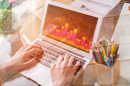 Close up of hands using laptop with abstract forex chart. Stock, finance and marketing concept....