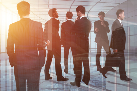 Crowd of young european businesspeople standing in modern glass office interior. Toned image. Meeting, teamwork and job concept. Double exposure の写真素材