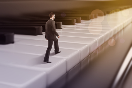 Young european businessman walking on abstract bokeh piano keys. Musician concept. 3D Rendering の写真素材