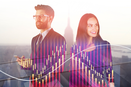 Attractive european businesspeople standing on abstract city background with forex chart and daylight. Teamwork, technology and trade concept. Double exposure の写真素材