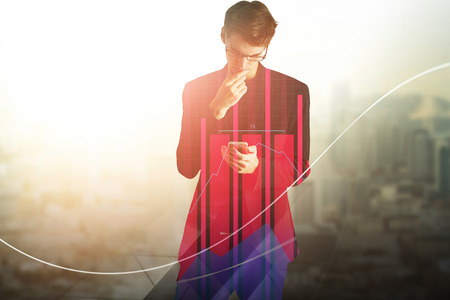 Portrait of handsome young european businessman using smart phone on bright city background. Technology and communication concept. Double exposure の写真素材