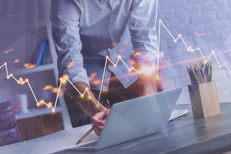 Hands using laptop with glowing forex chart on blurry background. Finance and marketing concept. Double exposure の写真素材