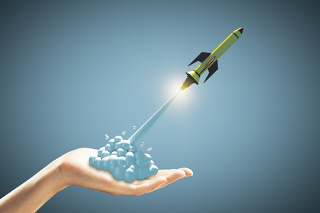 startup concept with green rocket flying out of human hand at blue background. 3D renderの写真素材