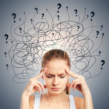 Portrait of confused young european female on gray background. Confusion and pensive conceptの写真素材
