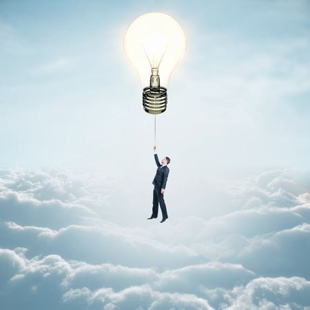 Businessman flying on lightbulb balloon on sky background with clouds. Idea and innovation conceptの写真素材