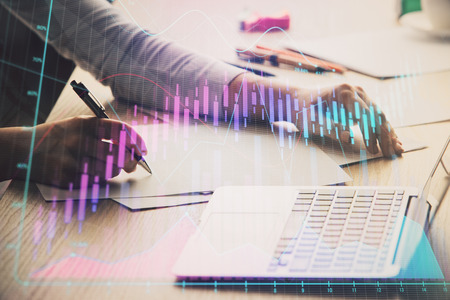 Close up of hands writing with double exposure of business charts. Financial concept.