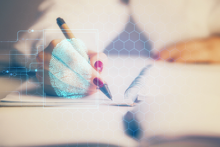 Blue fingerprint hologram over womans hands taking notes background. Concept of protection. Double exposureの写真素材