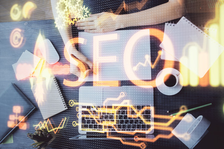 Multi exposure of womans hands making notes with SEO icon. Concept of Search engine optimizationの写真素材