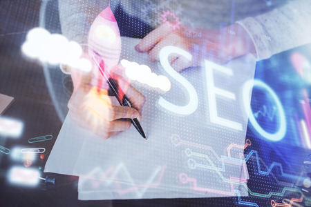 Multi exposure of womans hands making notes with SEO icon.の写真素材