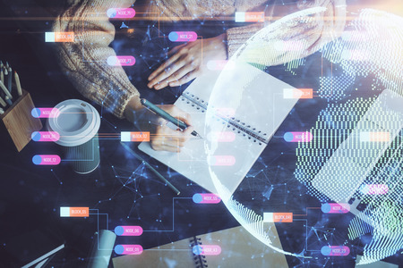 Double exposure of hands making notes with world map hologram and data theme icons. Concept of global computer data.の写真素材