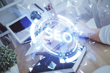 Multi exposure of womans hands making notes with SEO icon. Concept of Search engine optimizationの写真素材