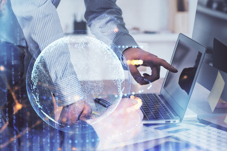 Double exposure of world map hologram with man working on computerの写真素材