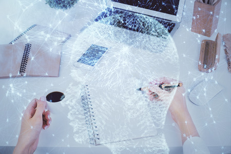 Double exposure of woman's writing hand on  with brain hud. Concept of learning.