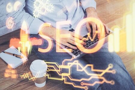 Multi exposure of seo icon with man working on computer on background. Concept of search engine optimization.の写真素材