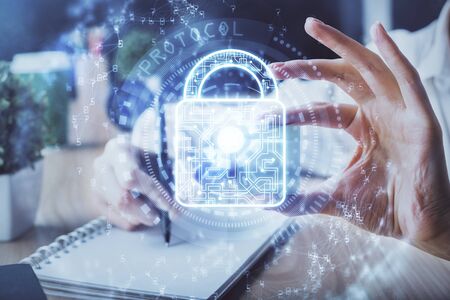Double exposure of womans hands writing with lock icon. Concept of security and protection of dataの写真素材