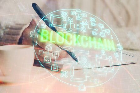 Cryptocurrency hologram over hands taking notes background. Concept of blockchain. Multi exposureの写真素材