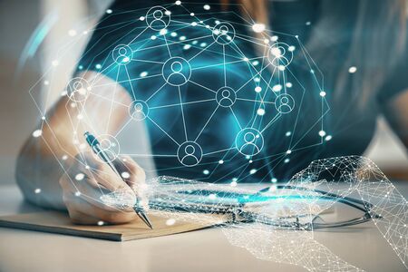 Social network theme hologram over hands taking notes background. Concept of global international...