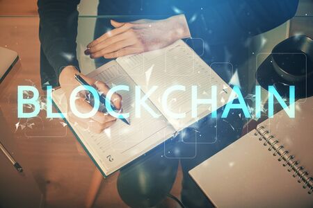 Cryptocurrency hologram over womans hands writing background. Concept of blockchain. Multi exposureの写真素材