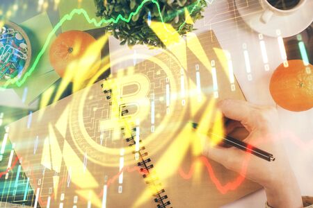 Cryptocurrency hologram over woman's hands writing background. Concept of blockchain. Multi exposureの写真素材