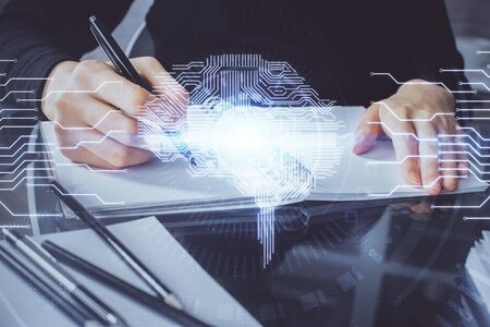 Double exposure of writing hand on background with brain hologram. Concept of learning.