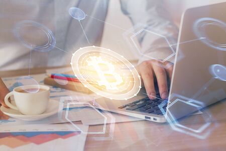 Crypto currency theme hologram with businessman working on computer on background. Concept of blockchain. Double exposure.の写真素材