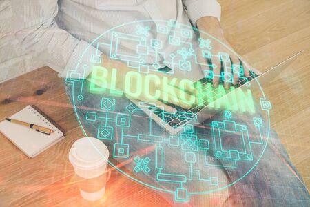 Crypto currency theme hologram with businessman working on computer on background. Concept of blockchain. Double exposure.の写真素材