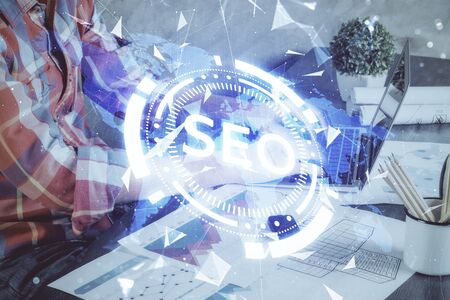 Multi exposure of seo icon with man working on computer on background. Concept of search engine optimization.の写真素材
