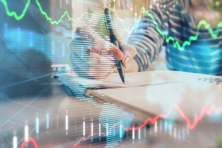 Financial forex graph drawn over hands taking notes background. Concept of research. Double exposureの写真素材