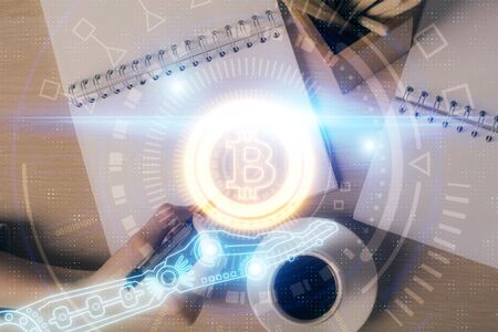 Cryptocurrency hologram over woman's hands writing background. Concept of blockchain. Double...