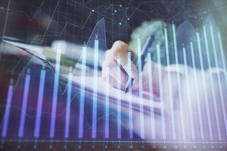 Financial forex graph displayed on hands taking notes background. Concept of research. Multi exposureの写真素材
