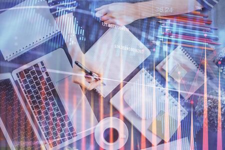 Financial forex graph drawn over hands taking notes background. Concept of research. Double exposureの写真素材